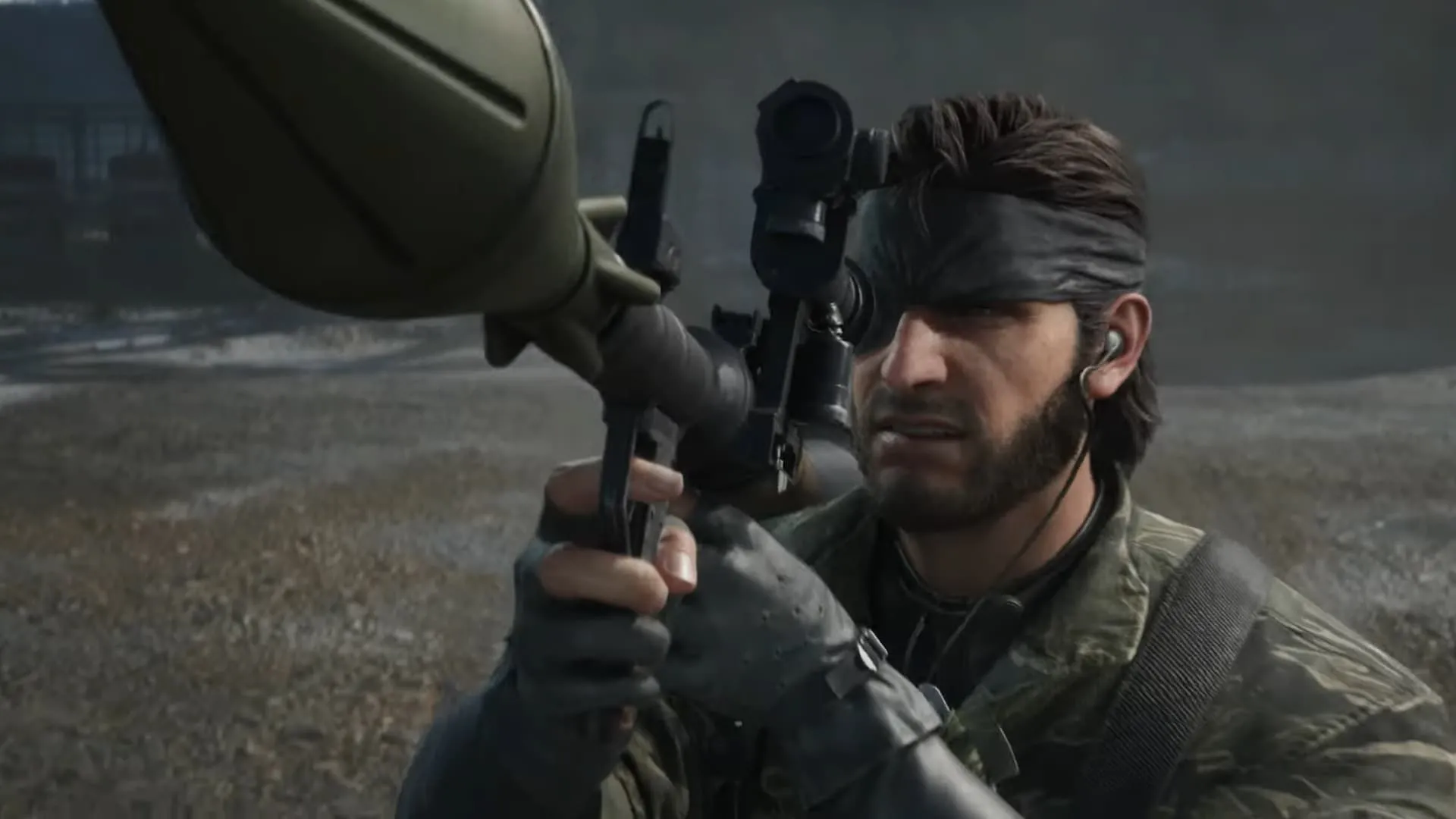 Snake di chuyển giữa làn khói trong Metal Gear Solid Delta Snake Eater, phía xa là bệ phóng tên lửa.
