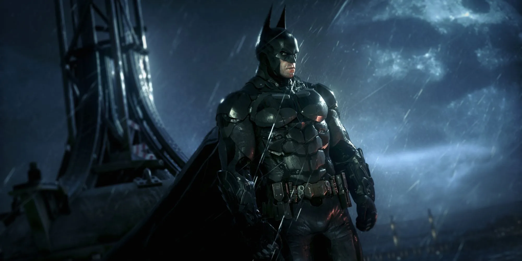 Batman đứng trên nóc một tòa nhà cao tầng nhìn xuống thành phố Gotham u ám trong Batman: Arkham Knight