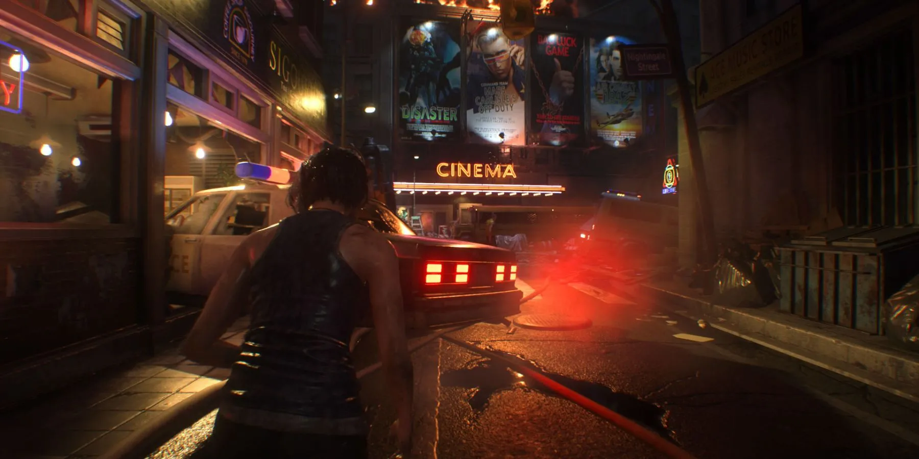 Jill Valentine trên đường phố với biển hiệu rạp chiếu phim và xe cảnh sát trong Resident Evil 3 Remake.