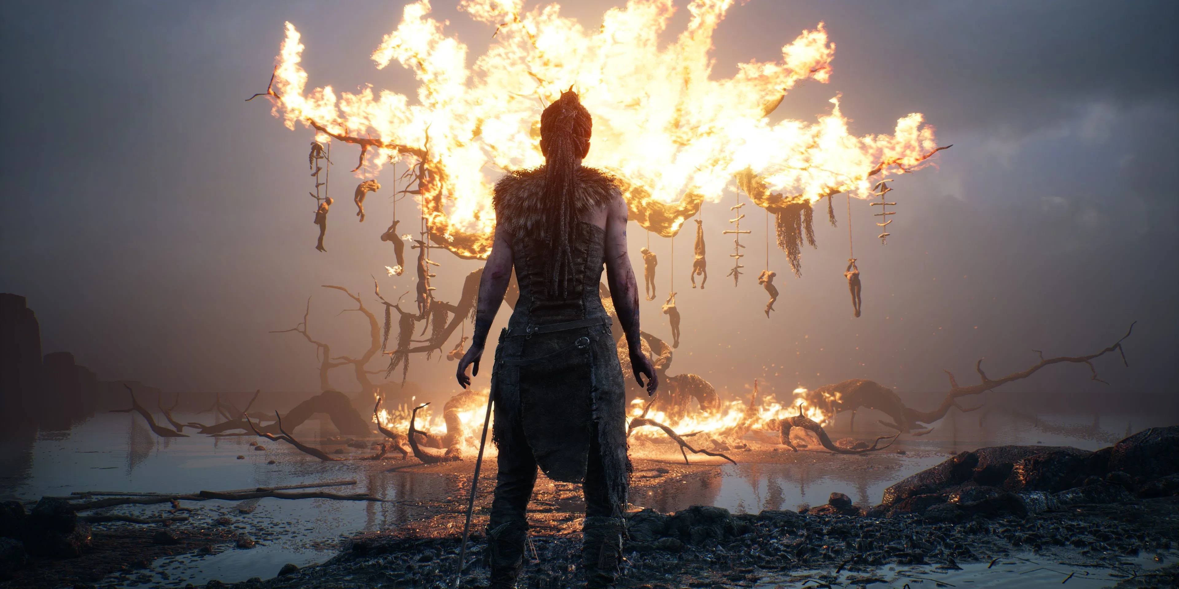 Senua đứng trước một cây cháy trong Hellblade: Senua's Sacrifice, cảnh tượng đầy ám ảnh
