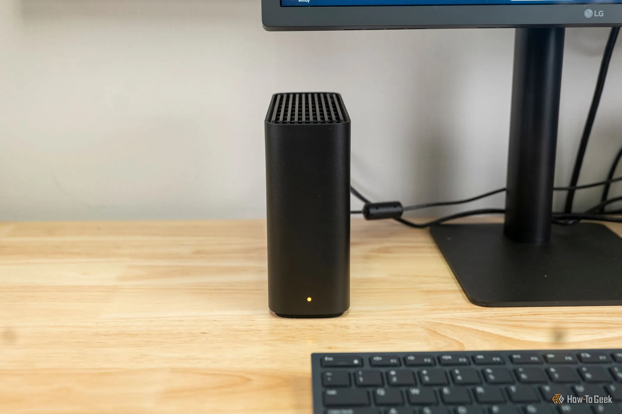 Synology BeeStation đặt cạnh màn hình máy tính, minh họa NAS cho lưu trữ ảnh tại nhà.