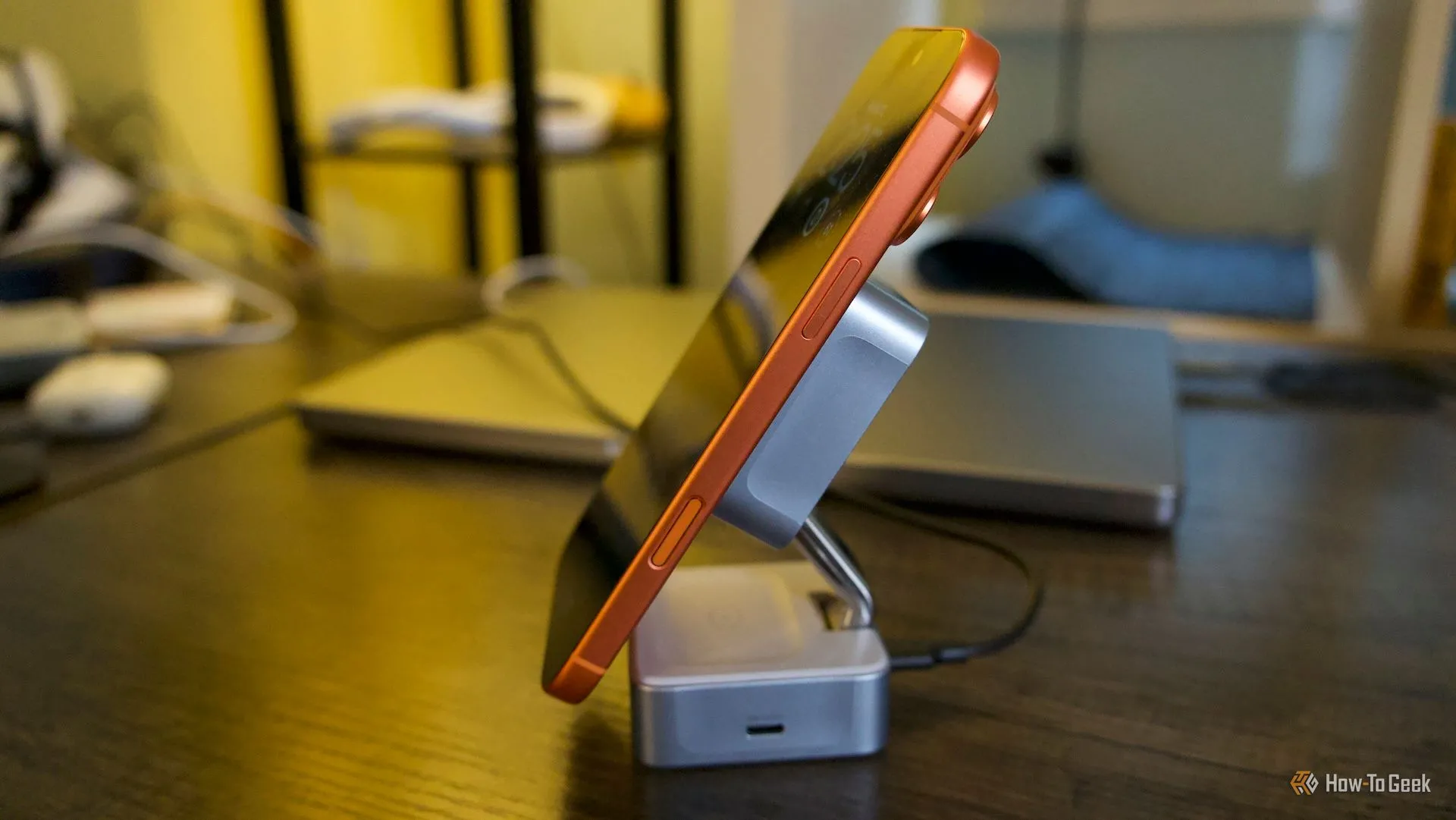 Ugreen MagFlow đặt nghiêng, hiển thị iPhone 17 Pro Max màu cam đang sạc trên đế 25W.